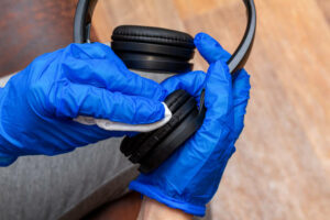 Cleaning, disinfecting, wiping music headphones with a hand in glove and napkin